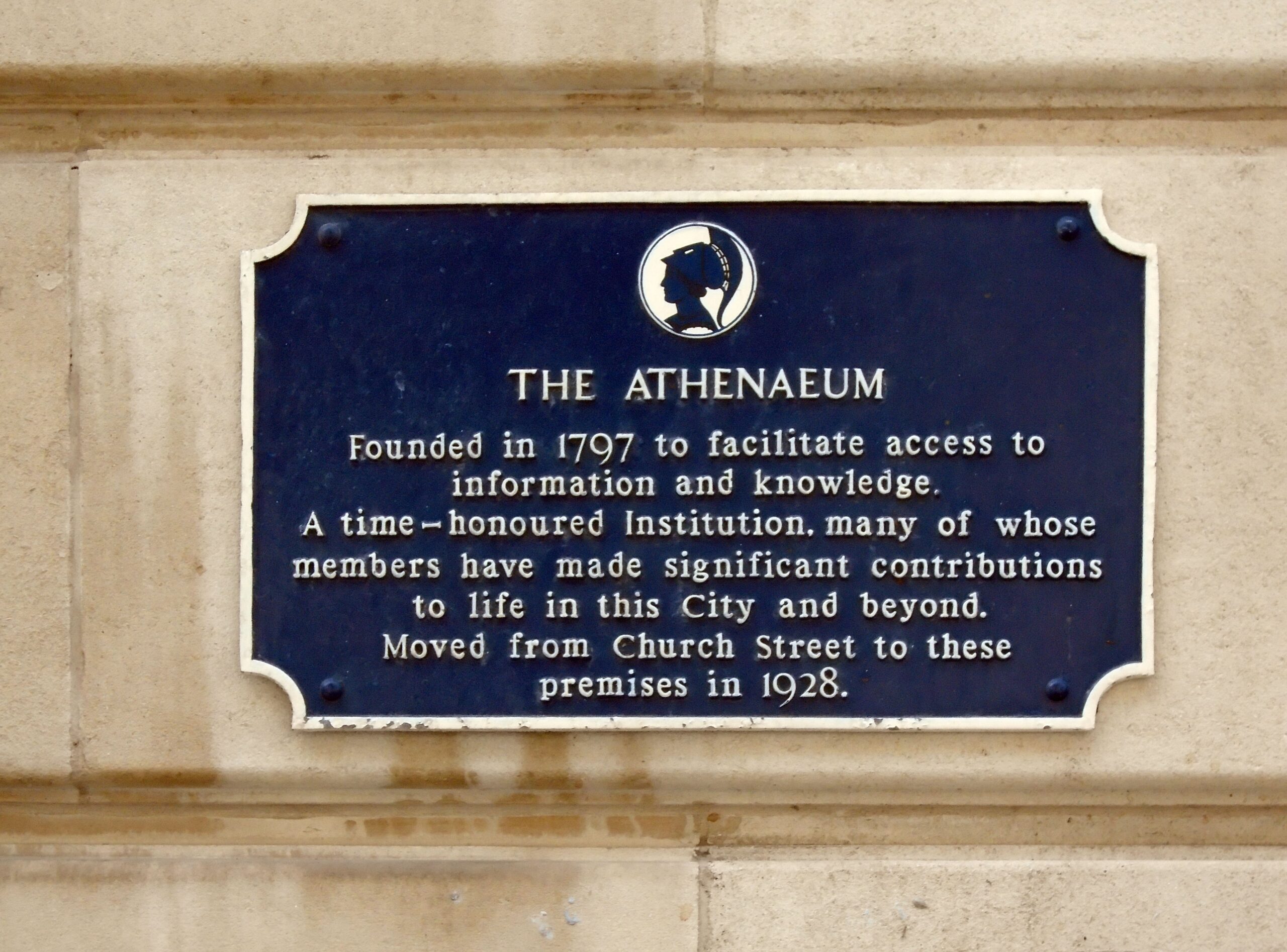 Blue heritage plaque for The Athenaeum in Liverpool mounted on a stone wall.