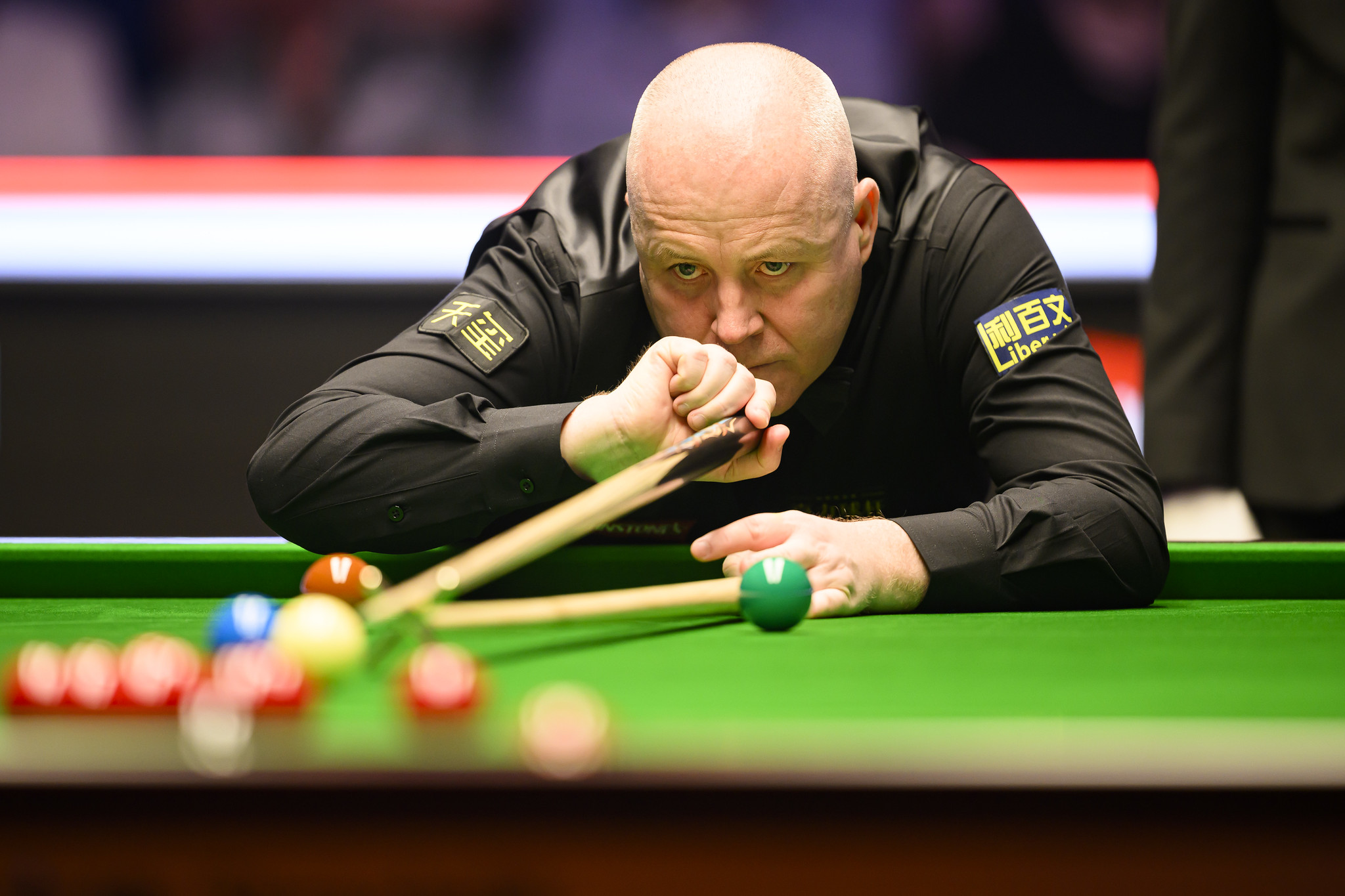 Snooker player aiming carefully at the cue ball during a match under tournament lighting